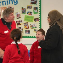 Anne stands in a class room, she is talking to two students and a teacher