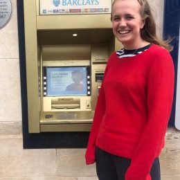 Millie standing with the golden cash point in Enfield - the first ATM machine in the world!